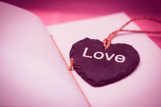 Red heart with the word love on it on top of a book