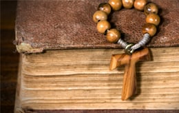 tau cross on top of a bible