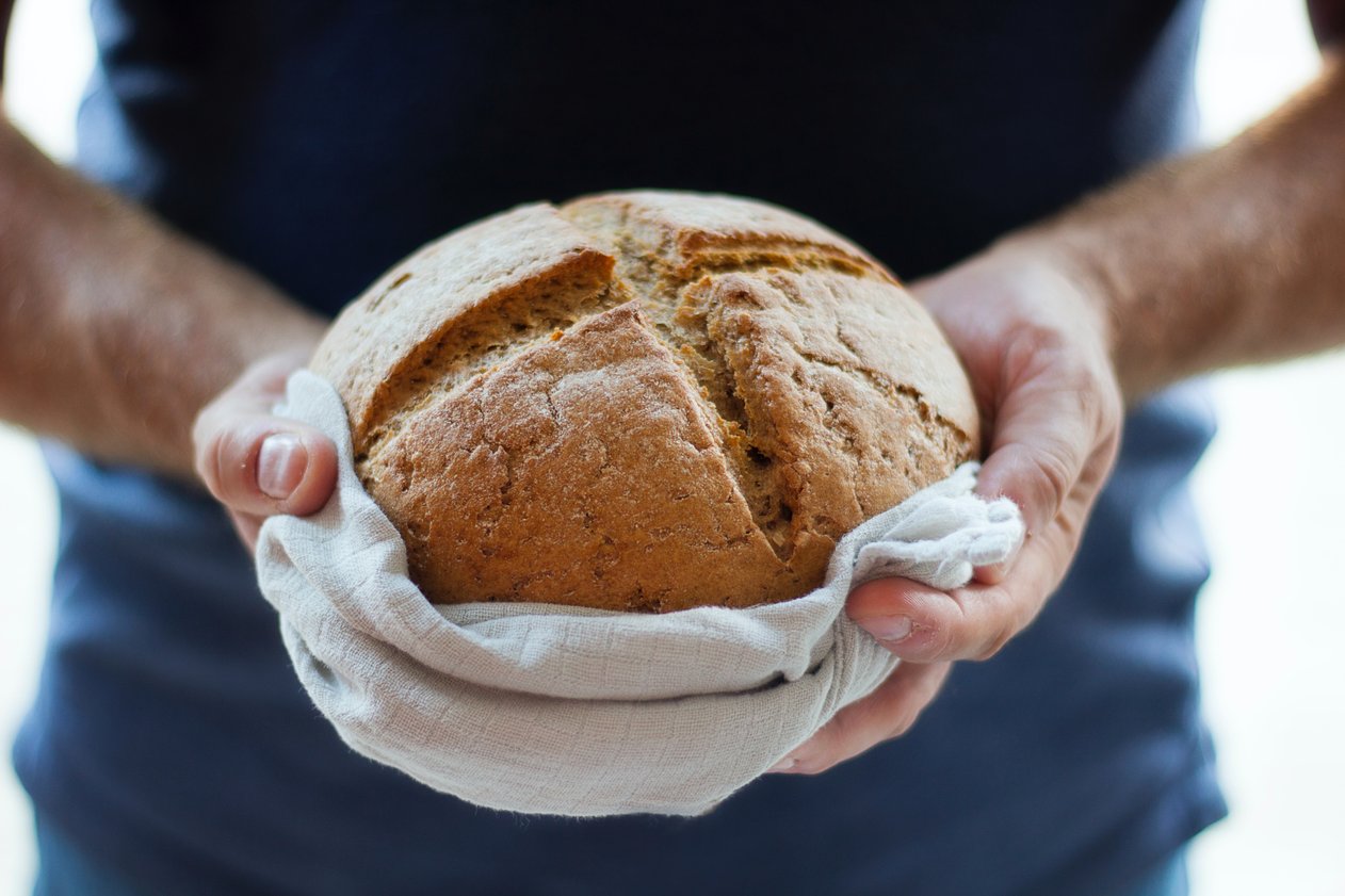 Man holding loaf of bread/Photo by Kate Remmer on Unsplash